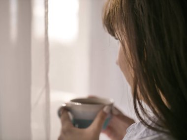 Genç esmer kız içecekler sabah kahve pencere dışarı bakıyor