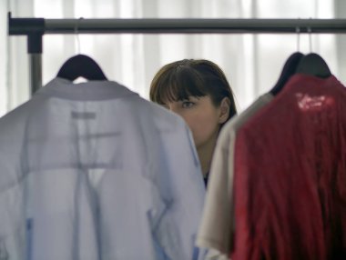Pretty esmer kadın askıları üzerinde giysi düşünüyor