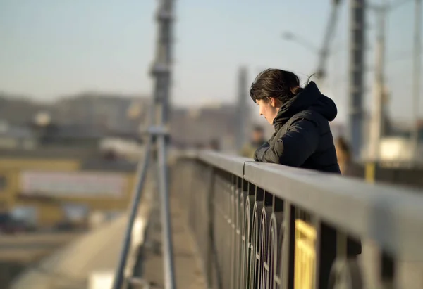 Solitaire jeune fille brune se tient sur le pont par une journée ensoleillée — Photo