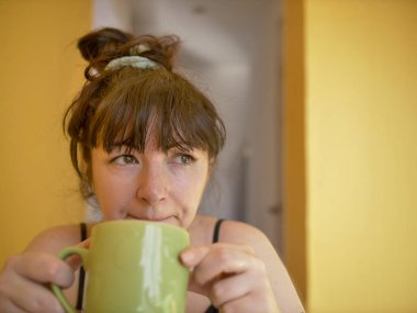 Evde sabah bir fincan kahve ile üzgün ve uykulu genç kadın