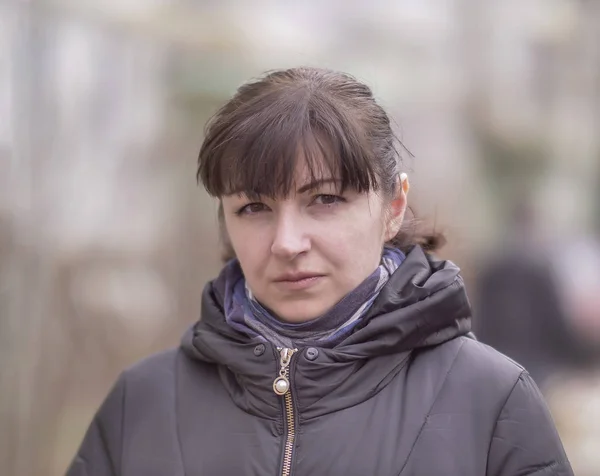 Porträt eines attraktiven brünetten Mädchens auf dem verschwommenen Hintergrund der Straße, das in die Kamera blickt — Stockfoto