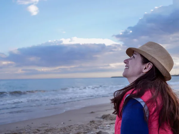 Jeune femme séduisante assise sur la plage souriant en regardant le ciel, copyspace — Photo