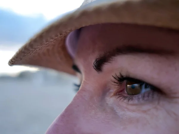 Yeux marrons souriants d'une jeune femme coiffée d'un chapeau, gros plan — Photo