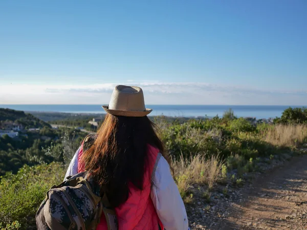 Touriste fille dans un chapeau et des lunettes de soleil va le long du chemin sur la colline — Photo