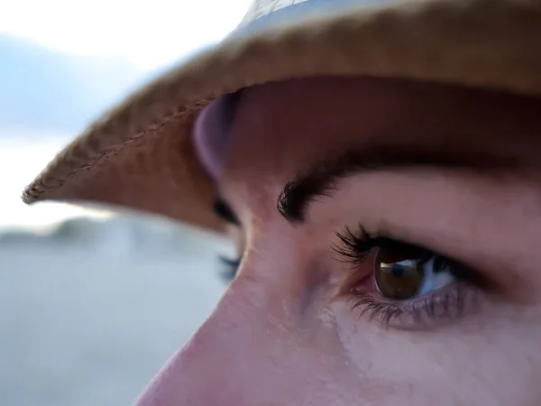 Yeux marron d'une jeune femme coiffée d'un chapeau regardant vers le côté, gros plan — Photo