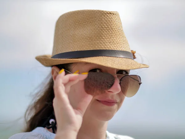 Jeune femme brune redresse les lunettes de soleil sur son visage, regard sexy, regarde dans la caméra — Photo