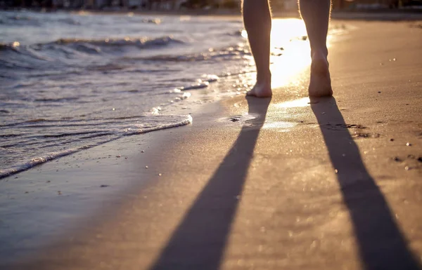 Un homme marchant le long de la plage au coucher du soleil, fond flou — Photo