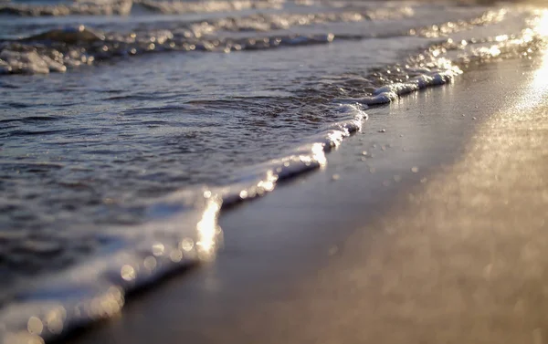 Les petites vagues de mer lavent la plage de sable au coucher du soleil — Photo