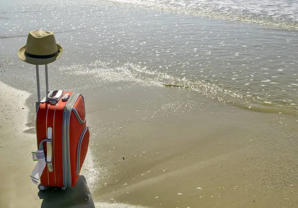 Valise rouge avec chapeau se tient sur le sable de la mer, espace pour le texte. Concept de vacances — Photo