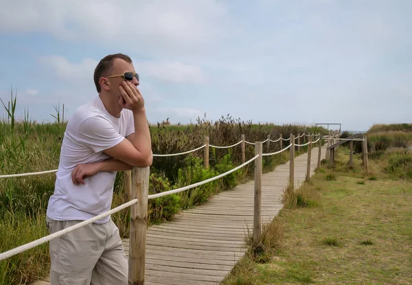 Jeune homme en lunettes de soleil se tient penser sur une piste de planches — Photo