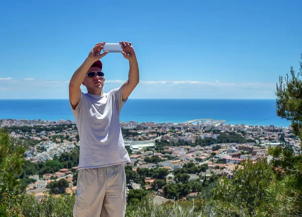 Jeune homme attrayant prend un selfie sur le fond d'une colonie au bord de la mer — Photo