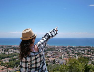 Şapkalı çekici turist, bir tepenin üzerinde duran, gökyüzüne onun önünde bir el gösterir