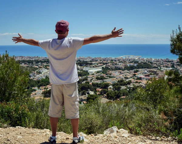 Un gars se tient sur une colline écartant les bras sur le côté, concept de voyage, liberté — Photo