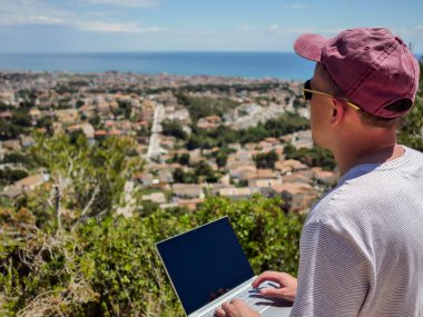 Freelancer adam açık havada çalışır deniz kenarında şehrin kendisi tarafından kendi önünde güzel sahne hayran, zevk içinde çalışmak
