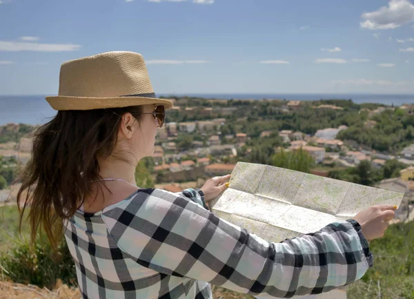 Une jeune voyageuse avec une carte de la région examine la ville devant elle . — Photo