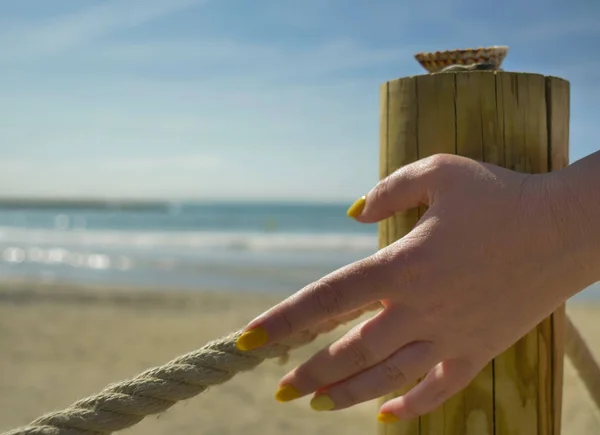 Main féminine touche une corde épaisse, route vers la mer, gros plan — Photo