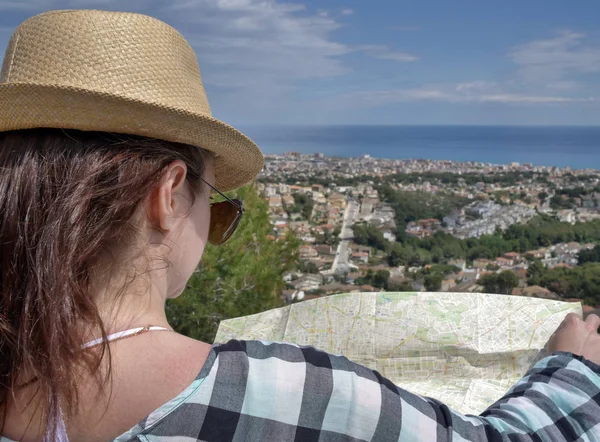 Jolie jeune femme brune avec une carte du village se trouve sur la colline en regardant la carte, gros plan — Photo