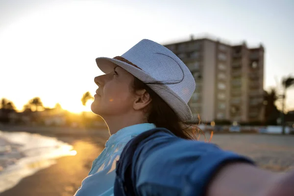 Portrait of a young woman in a white hat on the seashore enjoying vacation — Stock Photo, Image