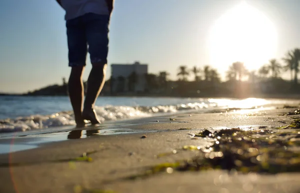 Silhouette floue des jambes masculines sur la plage au coucher du soleil . — Photo