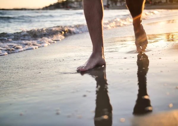 Pieds masculins marchant sur la plage au coucher du soleil, gros plan — Photo