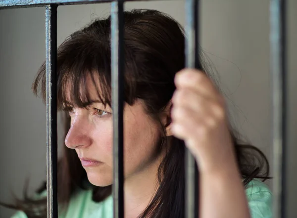A rapariga está presa na prisão, atrás das grades. Privação de liberdade Imagens Royalty-Free