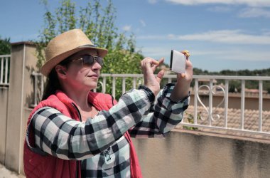 Şapkalı güzel bir kızın ellerinde beyaz bir cep telefonu.