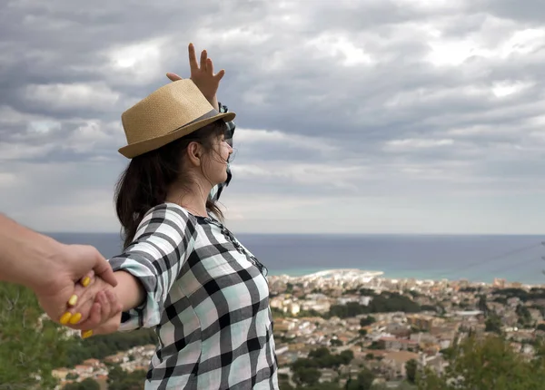 Une jeune touriste tient une main masculine et tient un chapeau. Suis-moi — Photo