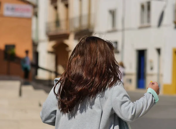 Brunette fille avec de longs cheveux brillants sur une rue de la ville par une journée ensoleillée — Photo