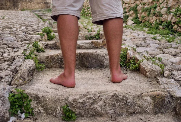 Un homme aux jambes bronzées pieds nus marche sur un escalier en pierre . — Photo