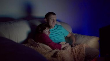 Evli çift gece geç saatlere kadar sarılıp televizyon seyrediyor.