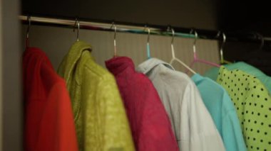 Bir adam elbise seçer, duvardaki dolapta, yakın plan.