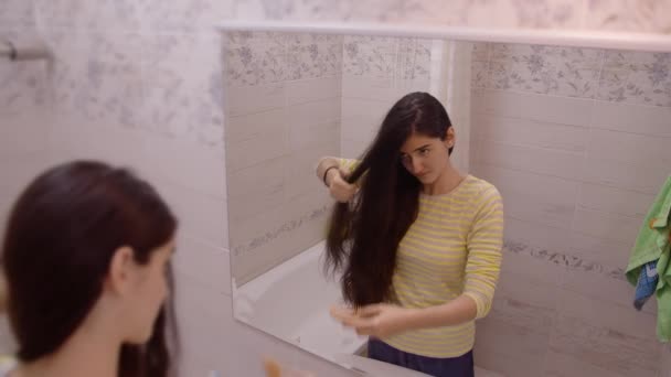 Hezká Dívka Teenager Stojí Koupelně Před Zrcadlem Česání Zcuchané Vlasy — Stock video