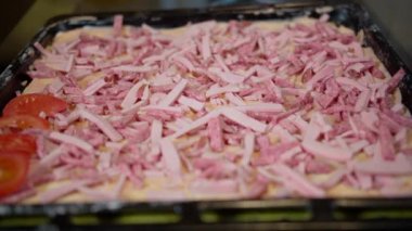 Ev yapımı pizza yapan adam pizzaya dilimlenmiş domates koyar.