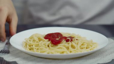 Bir adam ketçaplı spagetti döker ve onları yer.