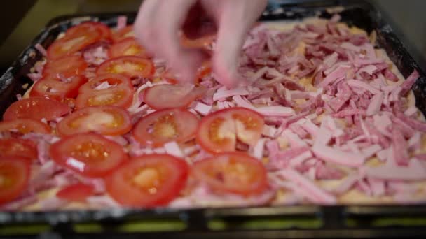 一个男人在做自制的披萨时 把新鲜切碎的西红柿放进披萨里 — 图库视频影像