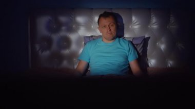 Yalnız bir adamın TV 'de sıkıcı bir akşam, yatakta oturuyor, kamera hareketi.