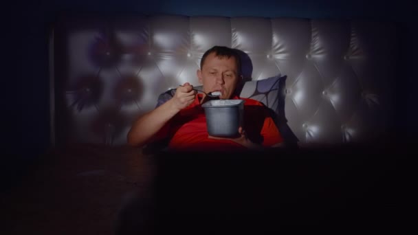 一个好人正在享受一个晚上，一边吃着美味的冰淇淋一边看电视 — 图库视频影像