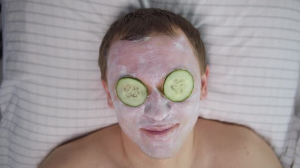 Homem Com Uma Máscara Cosmética Rosto Fatias Pepino Nos Olhos — Vídeo de Stock