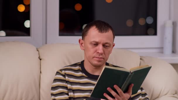 一个男人在深夜靠着窗户看一本旧书 — 图库视频影像