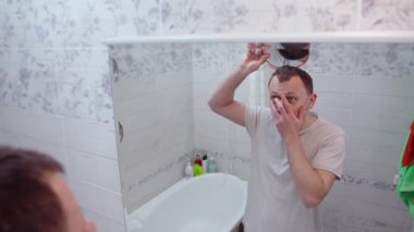 Orta yaşlı bir adam aynada kel kafasının yansımasını görünce şok olur.