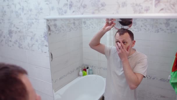 A middle-aged man is shocked to see the reflection of his bald head in the mirror — Stock Video