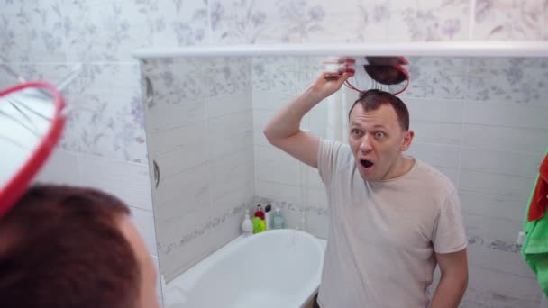 Medelålders Man Chockad Över Att Spegelbilden Hans Skalliga Huvud Spegeln — Stockvideo