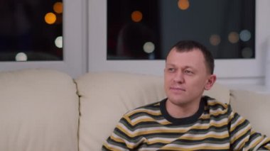 Çekici genç adam kanepede oturuyor ve televizyon seyrediyor, boşluğu kopyalıyor.