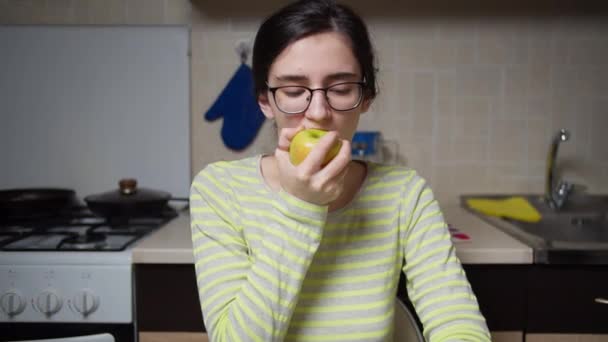 Menina Bonito Com Óculos Morde Uma Maçã Sentado Mesa Cozinha — Vídeo de Stock