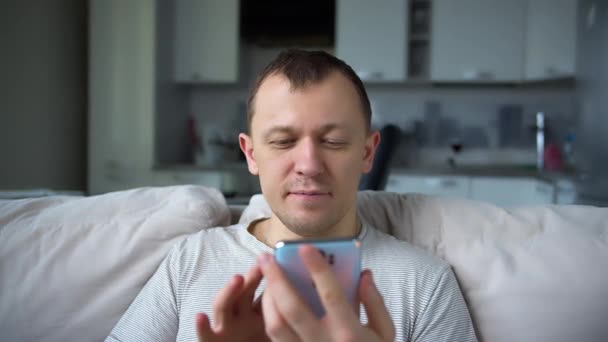 Sonriente Hombre Sentado Sofá Con Teléfono Móvil Sus Manos Pone — Vídeos de Stock