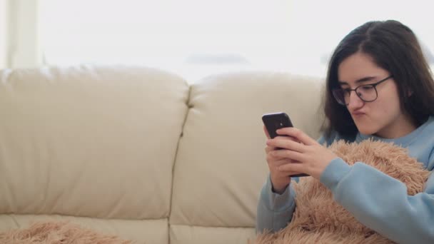 Nettes Mädchen Mit Brille Sitzt Tagsüber Auf Der Couch Und — Stockvideo