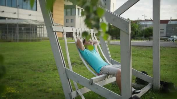 Jovem Descansa Banco Dia Ensolarado Movimento Câmera — Vídeo de Stock