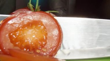 Kırmızı domatesler büyük bir aşçının bıçağıyla kesilir tahtada, makroda, su damlalarında.
