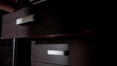 Bir soyguncunun elleri rafları açar ve gizli para bulur, kamera hareketi.
