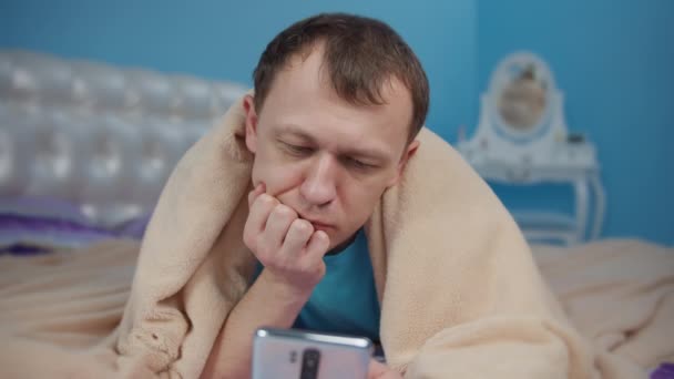 Молодой Человек Лежит Кровати Используя Свой Мобильный Телефон — стоковое видео